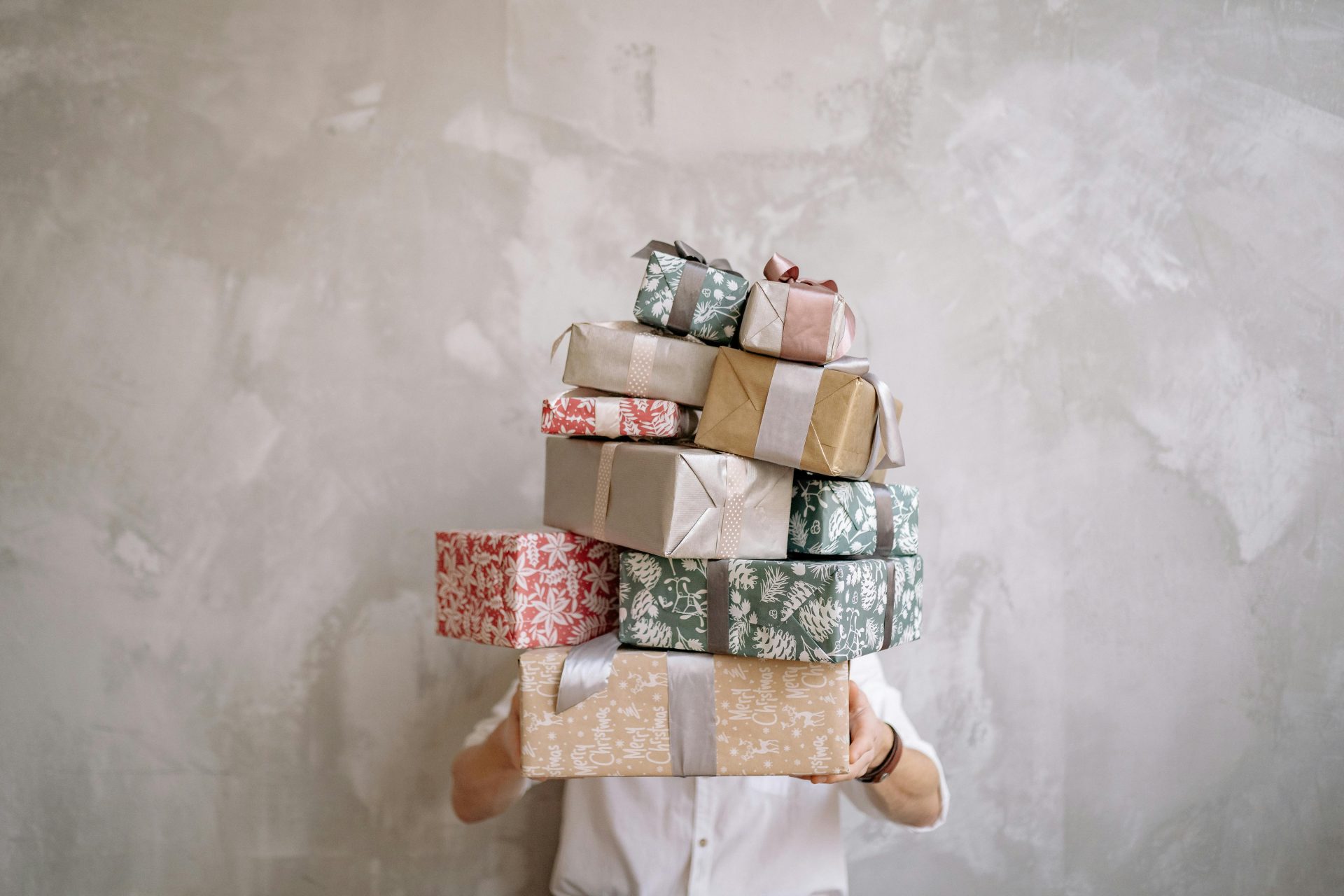A man holding a pile of beautifully wrapped gifts